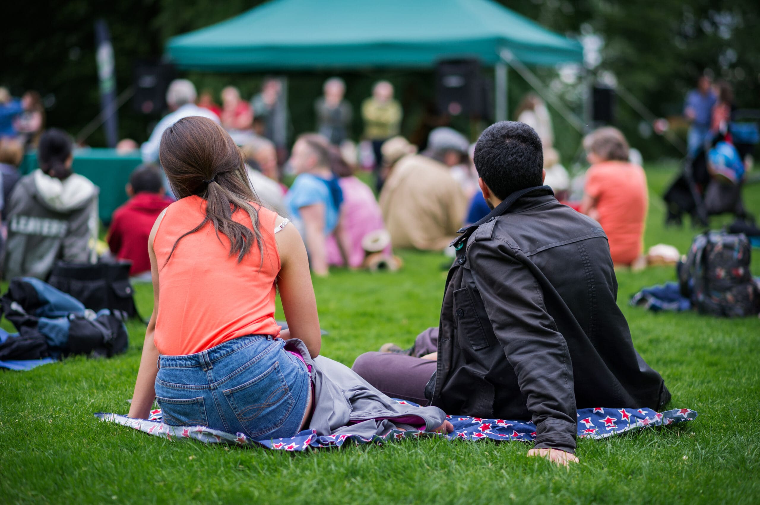 Friends sitting on the grass, enjoying an outdoors music, culture, community event, festival. Friends sitting on the grass, enjoying an outdoors music, culture, community event, festival.